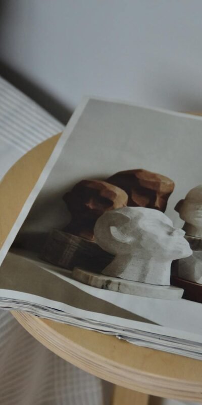 A stylish magazine with art sculptures on a wooden stool, perfect for decor inspiration.