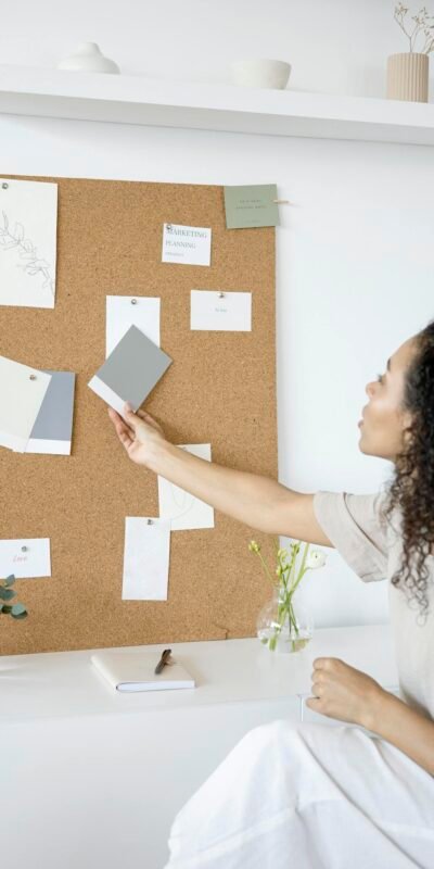 A woman curates a mood board in a minimalist home office setting, blending creativity and productivity.